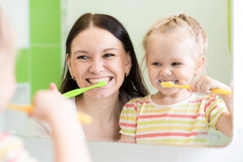 mother and child brushing teeth together in bathroom