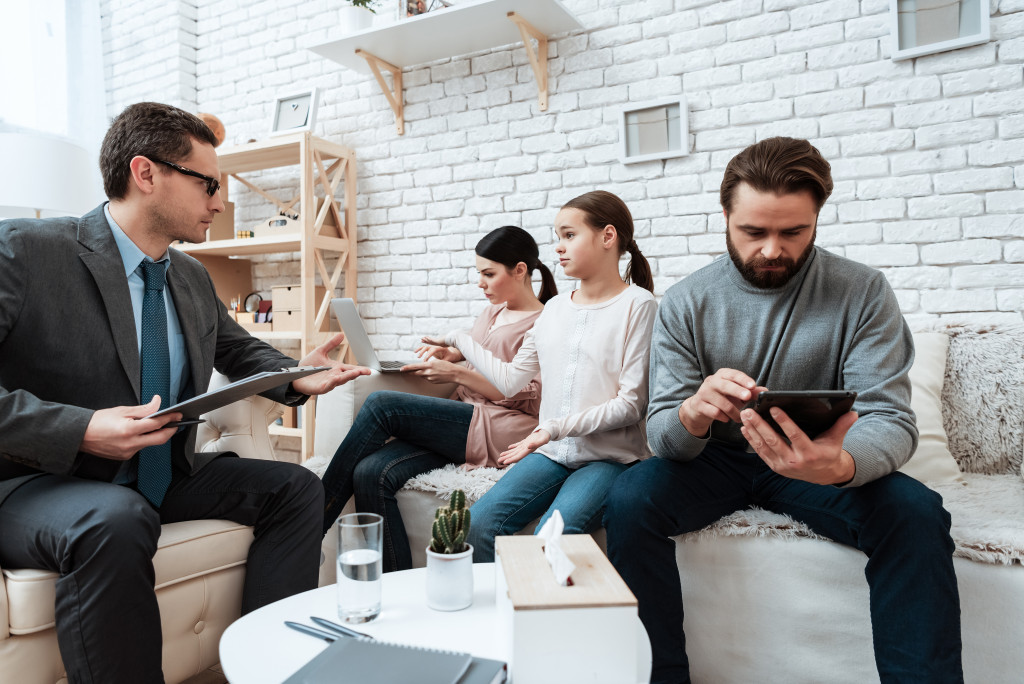 A family is seen to be discussing some things with someone who appears to be their lawyer.