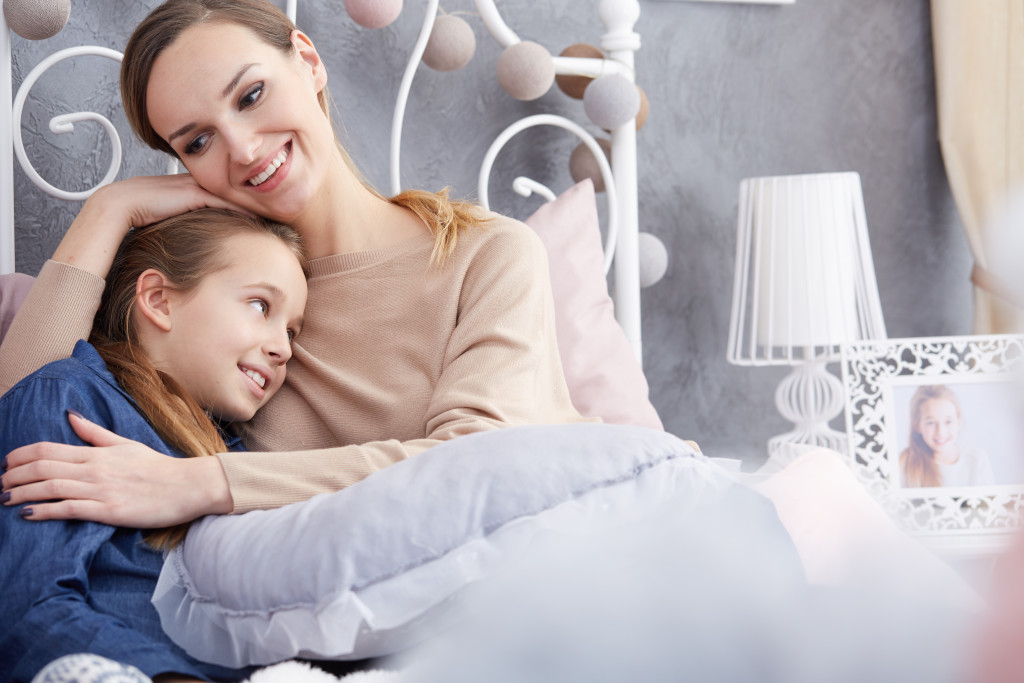 mother smiling talking to her daughter in bed